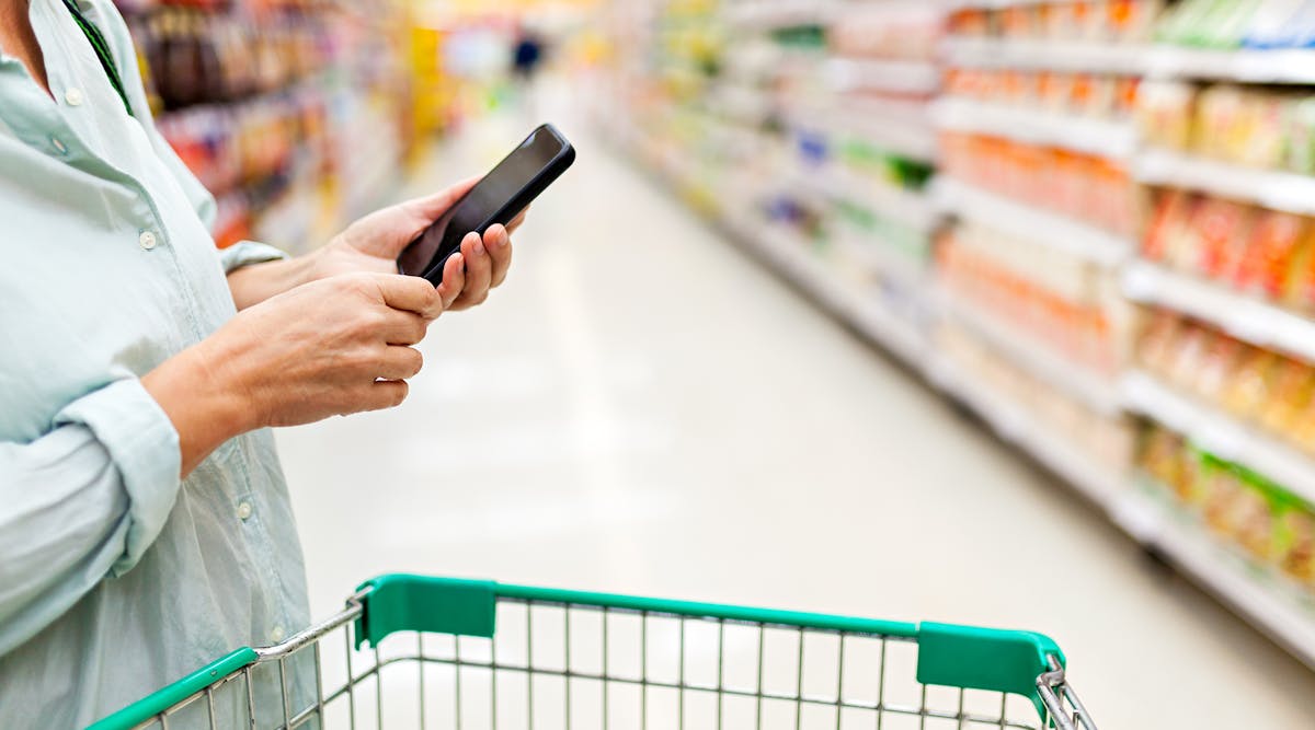 Woman using smartphone in supermarket