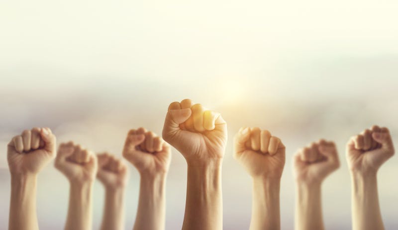 Peoples raised fist air fighting and sunlight effect, Competition, teamwork concept.