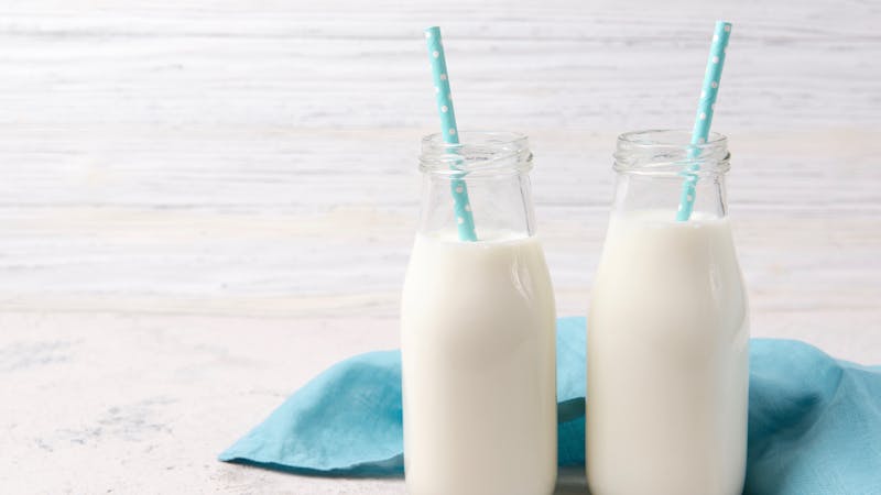 Dos botellas de leche fresca con pajitas azules