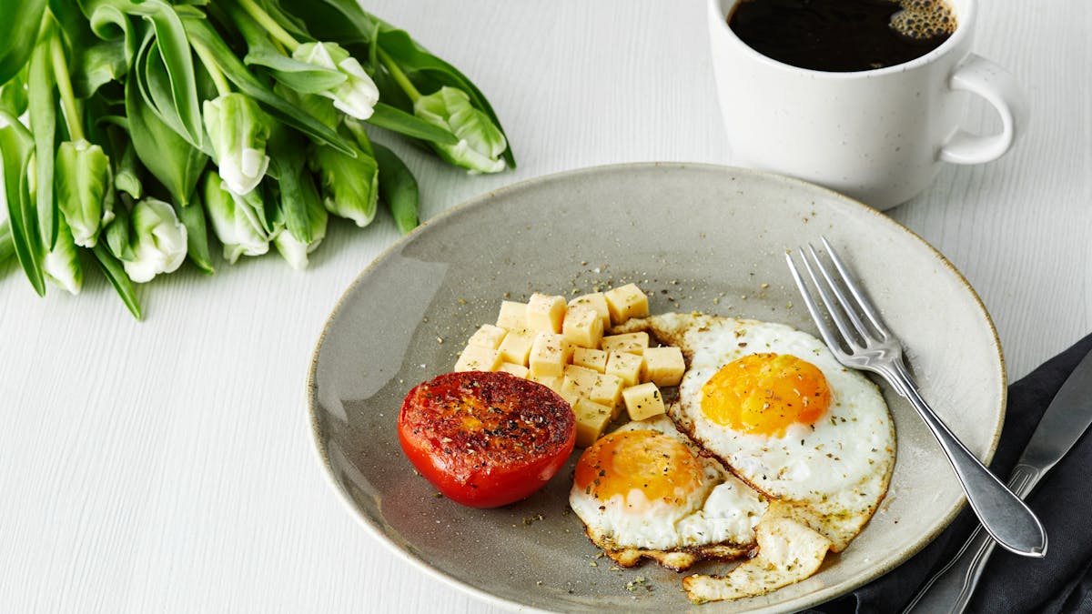 Desayuno con huevos fritos, tomate y queso