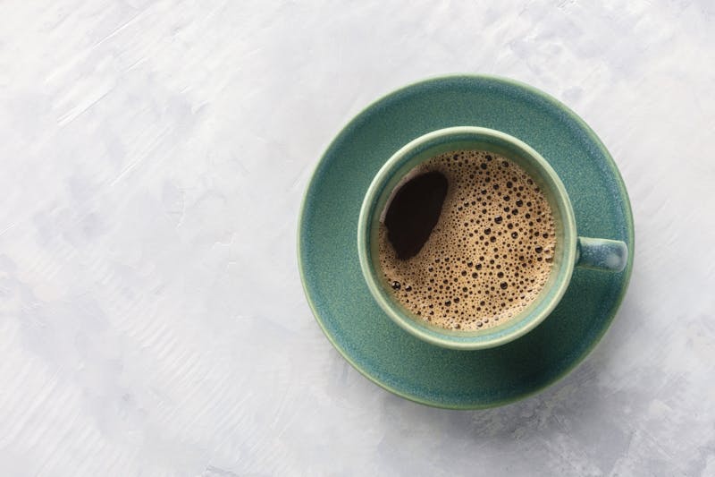 A cup of black coffee, shot from the top on an abstract gray background with copyspace