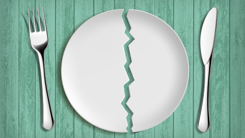 Broken white plate on a green wooden table. Healthy eating