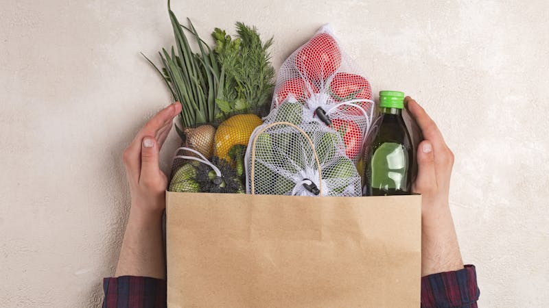 Man holds products in a paper bag. Vegetables in the range of shopping in the terrestrial and online store. top view
