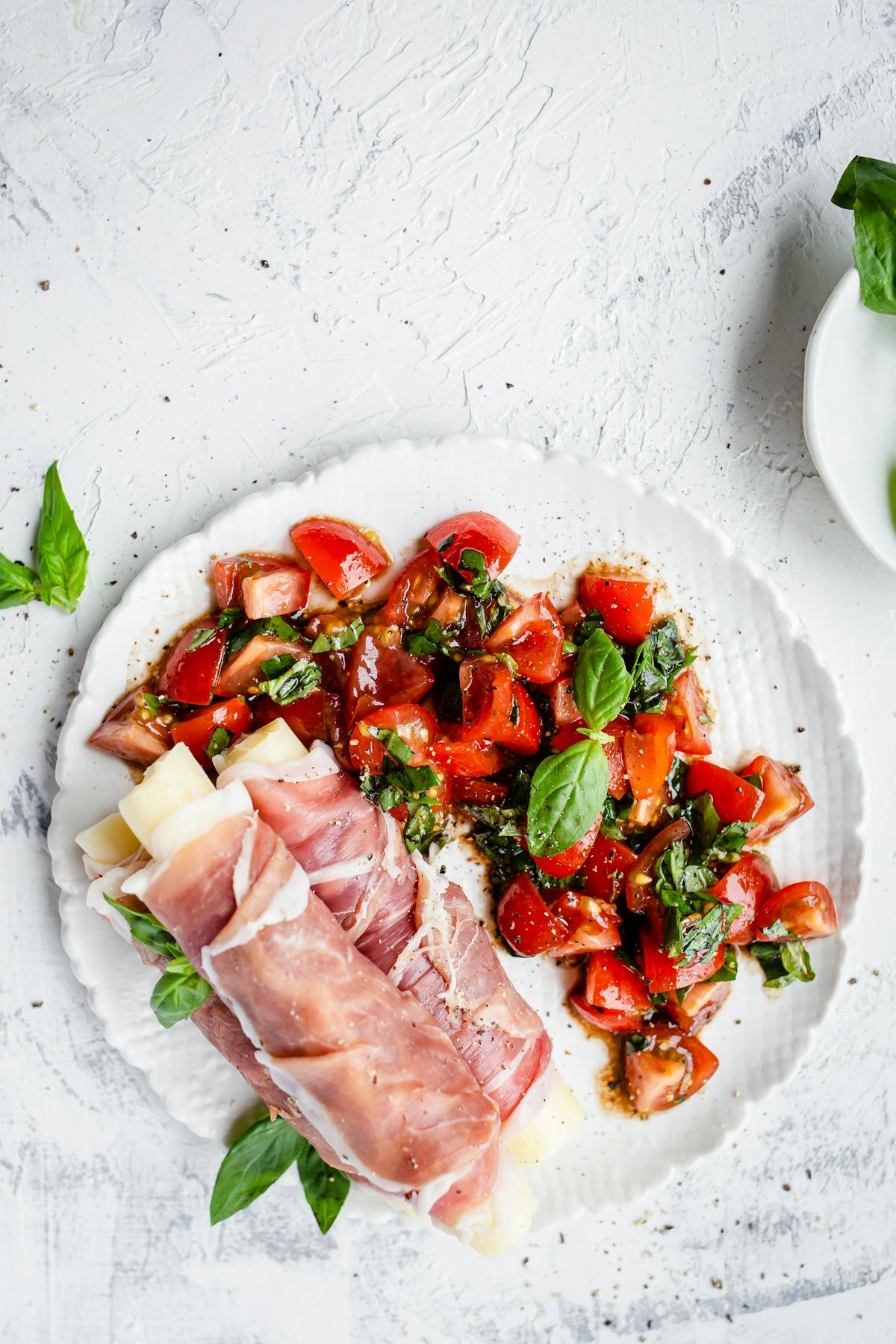 Palitos de mozzarella envueltos en prosciutto con ensalada de tomate y albahaca
