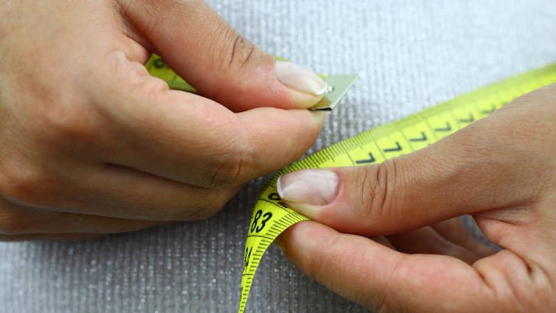Person measuring their waste line