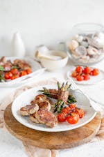 Chuletas de cerdo con judías verdes enrolladas en bacon y tomates asados