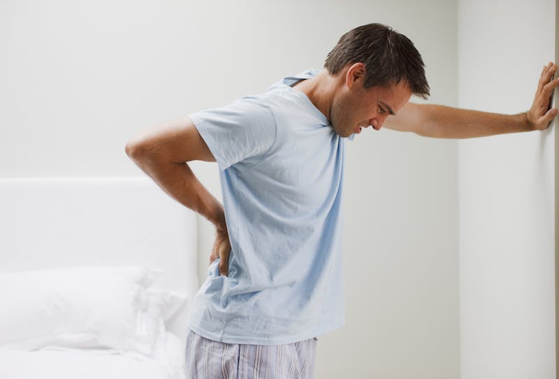 Man with backache leaning against wall