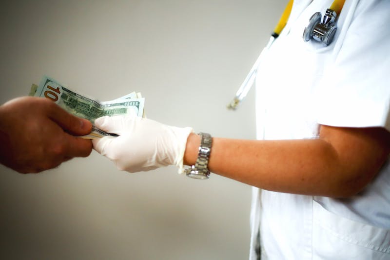 Doctor in white coat with stethoskop is offered money