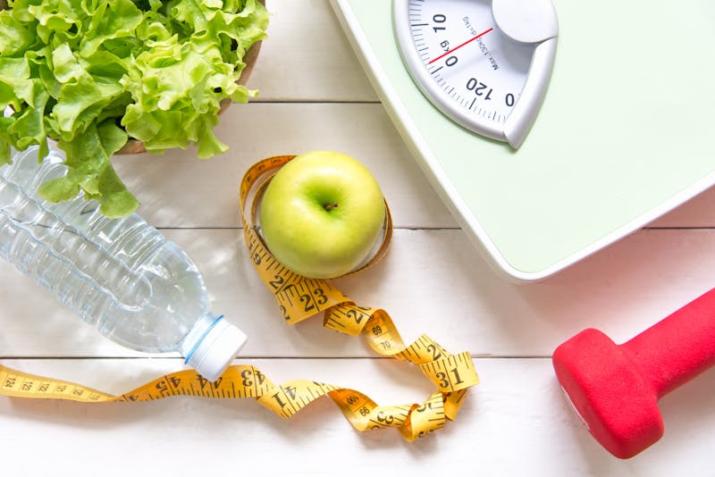 Green apple and Weight scale,measure tap with fresh vegetable, clean water and sport equipment for women diet slimming.  Diet and Healthy Concept