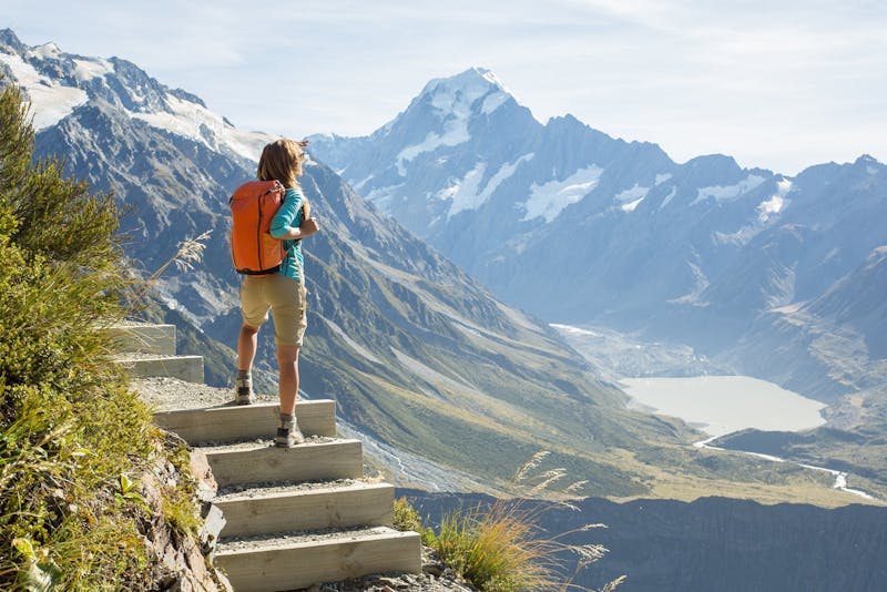 Hiker stands on a mountain top and admires view