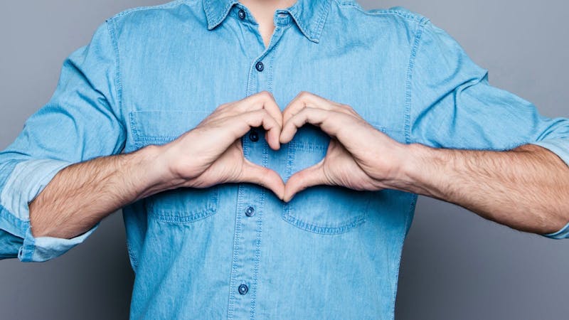 Portrait of happy handsome man in glasses making heart with fingers
