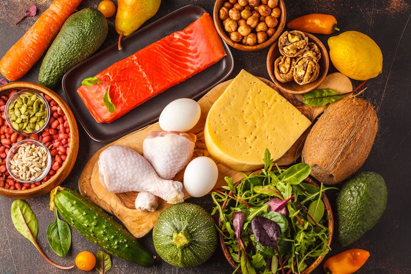 Keto (ketogenic) diet concept. Balanced low-carb food background. High protein food. Vegetables, fish, meat, cheese, nuts on a dark background.
