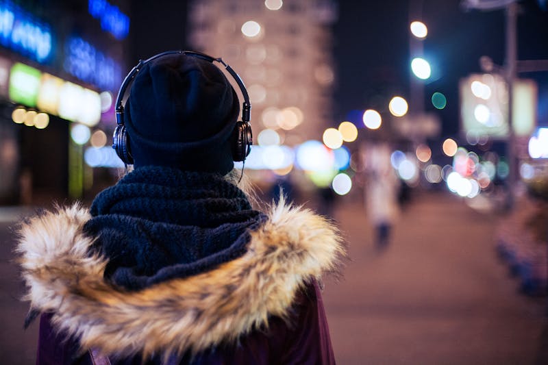 Girl walking through night city street listening to the music