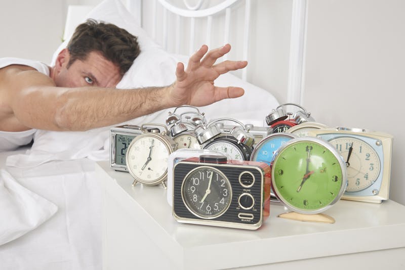 Man shutting off alarm clocks