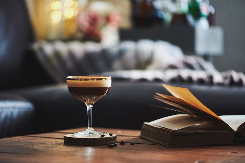 Espresso martini cocktail in indoor setting with coffee beans and book on coffee table