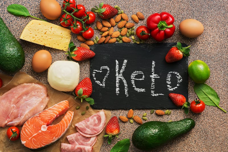 Keto diet food. Healthy low carbs products.Keto diet concept. Vegetables, fish, meat, nuts, seeds, strawberries, cheese. Top view. Signboard.