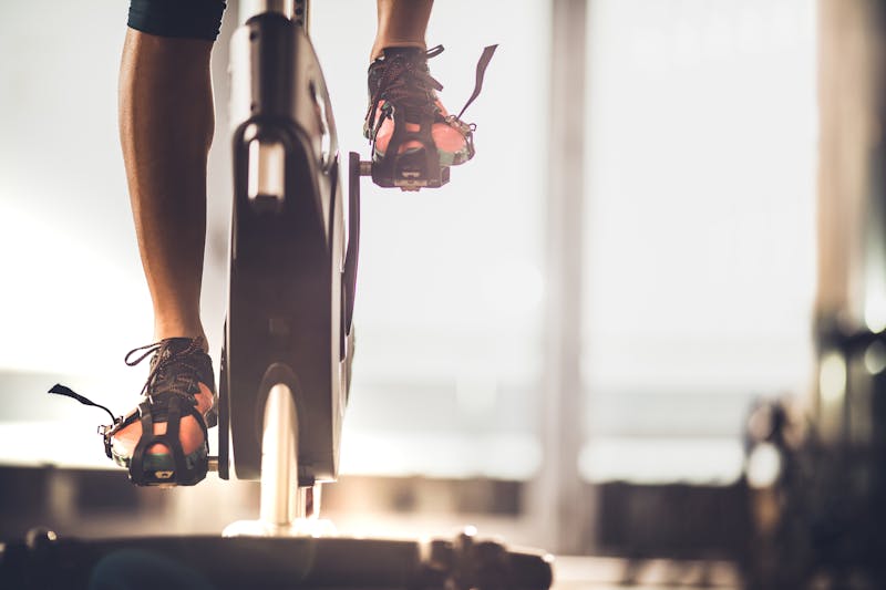 Unrecognizable female athlete exercising on exercise bike in a gym.