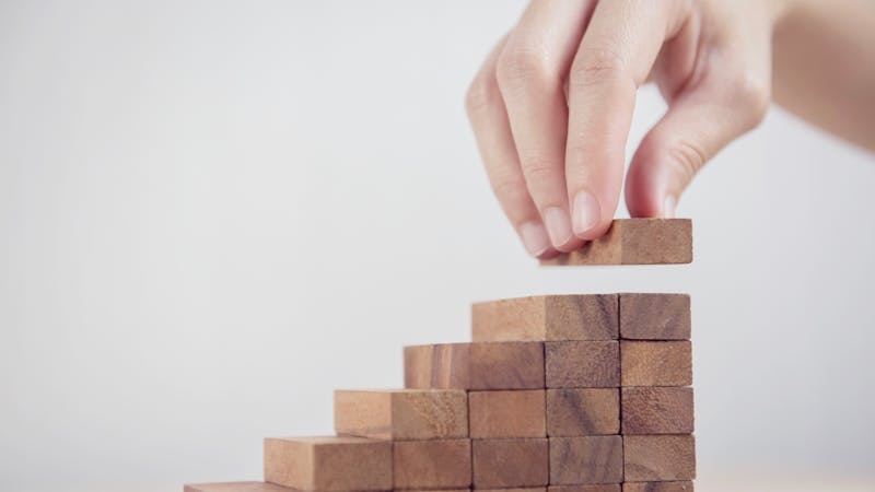 Woman hand arranging wood block stacking as step stair. Business concept growth success process.