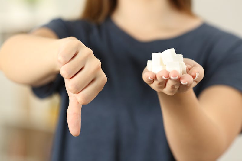 Woman hand holding sugar cubes with thumbs down