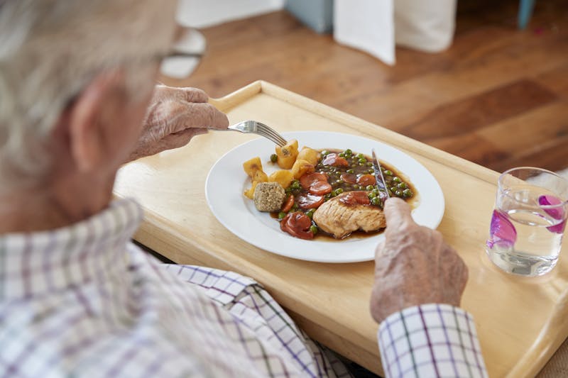 Over shoulder view of senior man eating dinner at home