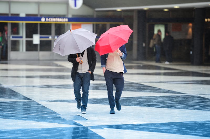 Pedestrians and umbrella in hard wind