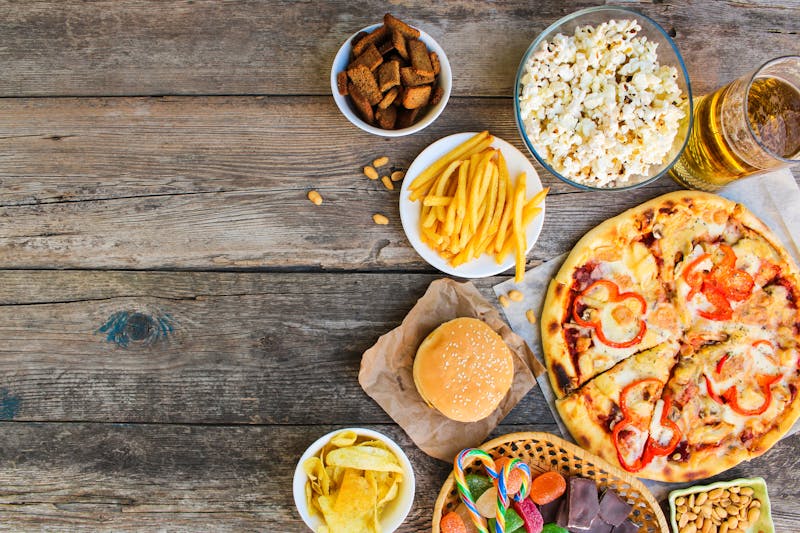 Fast food on old wooden background. Concept of junk eating. Top view.