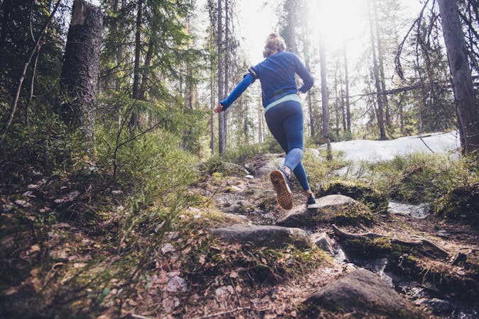 Woman trail runner running in forest.