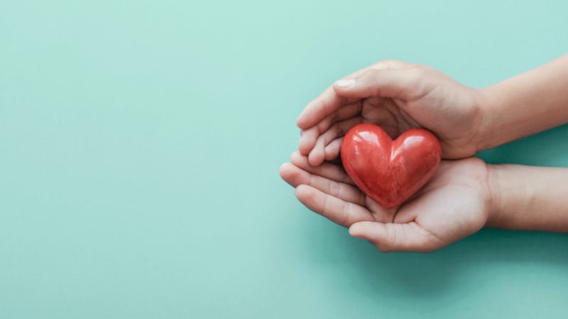 hands holding red heart on blue background, health care, love, organ donation, family insurance and CSR concept, world heart day, world health day