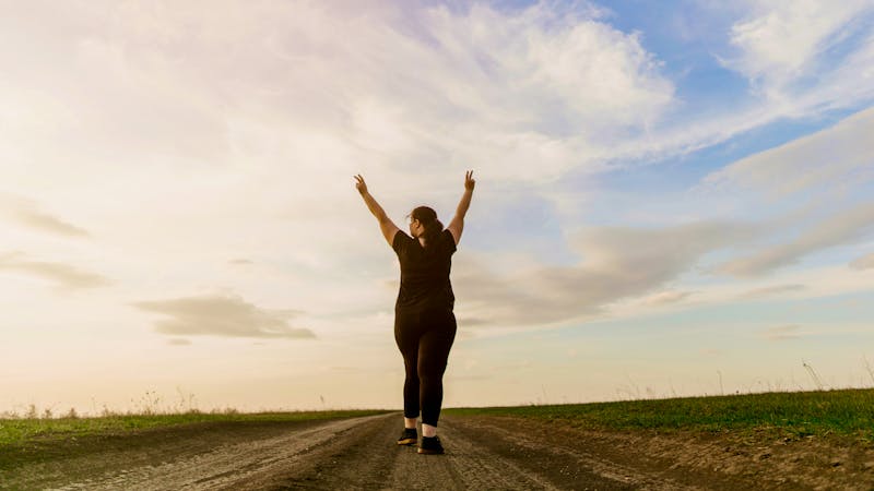 Overweight woman celebrating rising hands to sky
