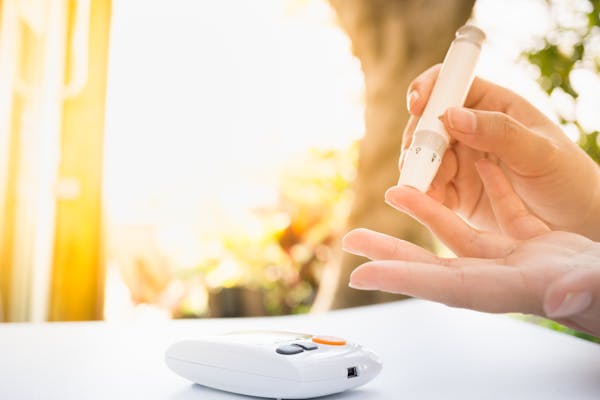 Medicine, Diabetes, Glycemia, Health care and people concept – close up of female using lancelet on  finger to checking blood sugar level by Glucose meter