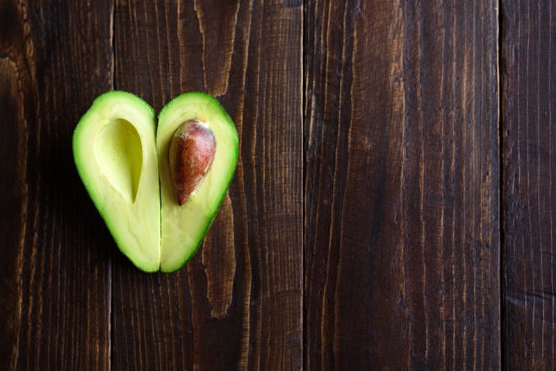 Heart shaped avocado on wooden background