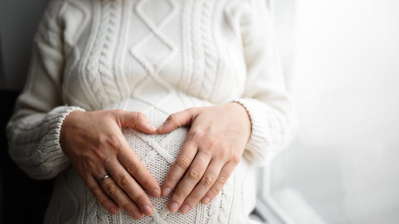 Hands in shape of heart on belly of pregnant woman