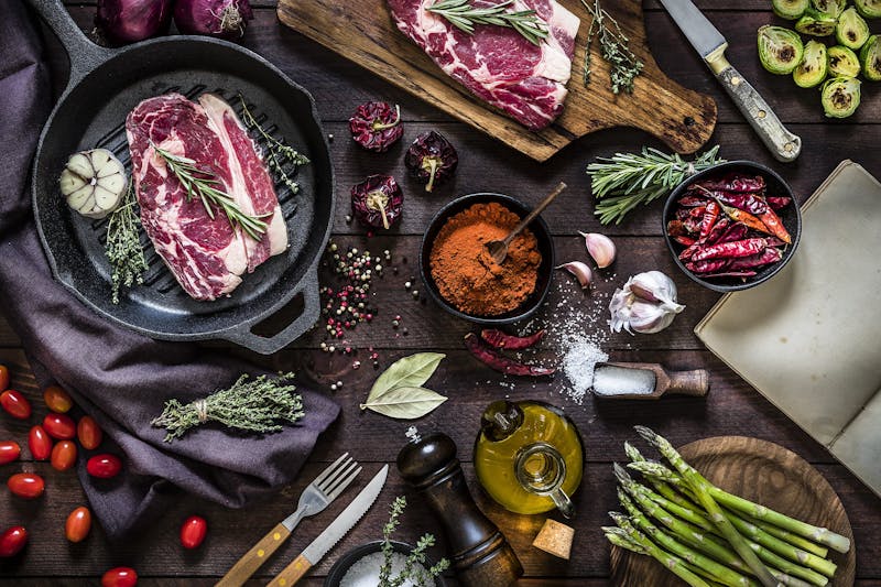 Roasting beef steaks and vegetables on an iron grill