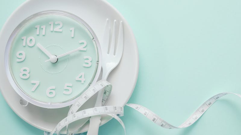 Blue clock on white plate, Intermittent fasting concept, ketogenic diet, weight loss, skip meal