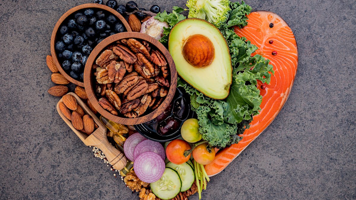 Heart shape of ketogenic low carbs diet concept. Ingredients for healthy foods selection on dark stone background. Balanced healthy ingredients of unsaturated fats for the heart and blood vessels.