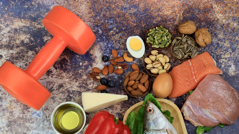 Ketogenic diet food and Balanced low-carb food as weight loss concept with dumbbell as Vegetables, fish, meat, cheese, nuts on teble background