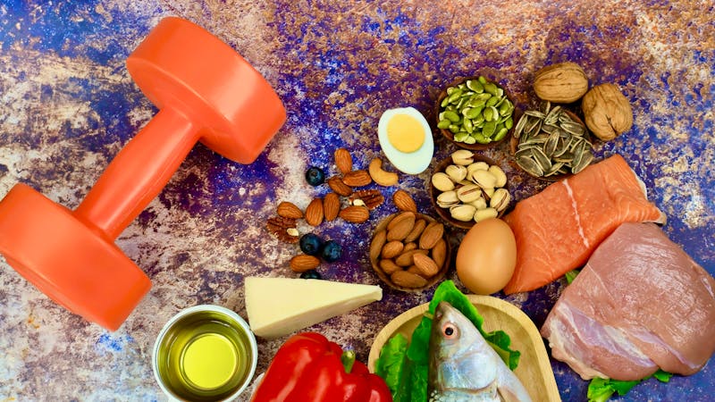 Ketogenic diet food and Balanced low-carb food as weight loss concept with dumbbell as Vegetables, fish, meat, cheese, nuts on teble background