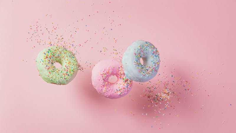 Sweet and colourful doughnuts with sprinkles falling or flying in motion