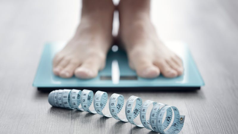 Feet on bathroom scale with tape measure