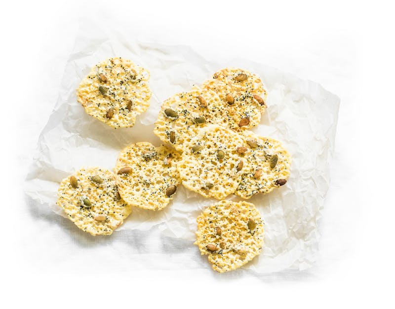 Homemade cheese chips with pumpkin seeds on a light background, top view