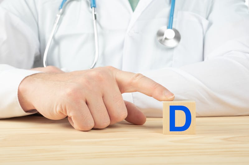 essential vitamins and minerals for humans. vitamin D alphabet on wood cube. doctor recommends taking vitamin D. doctor talks about the benefits of vitamin D. D Vitamin – Health Concept.
