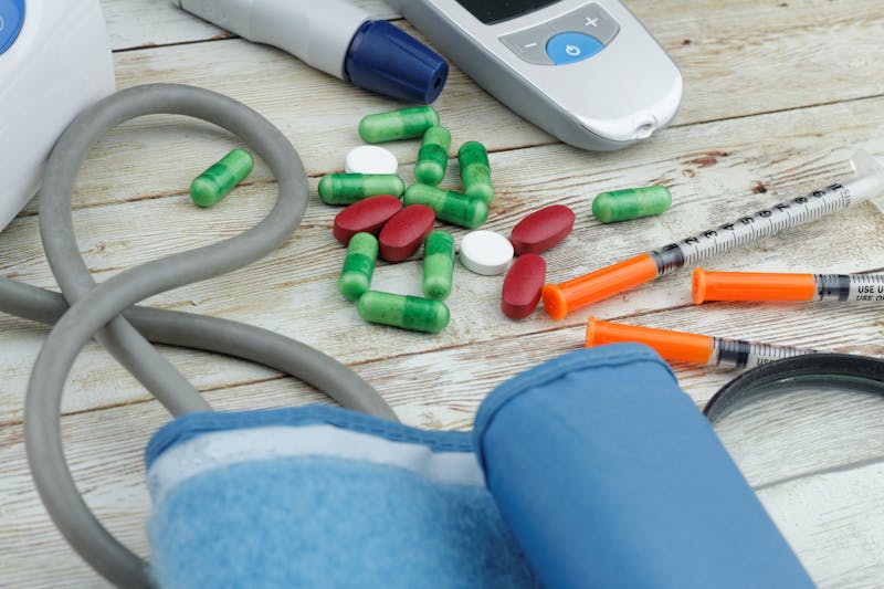 Healthcare concept with medicine and syringes on the table together with blood glucose monitor and blood pressure monitor