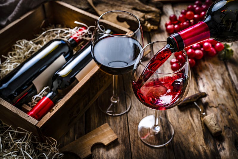 Pouring red wine into a glass on rustic wooden table