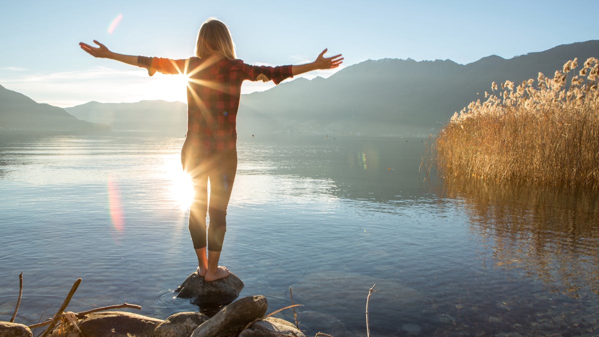 Young woman embracing nature, mountain lake