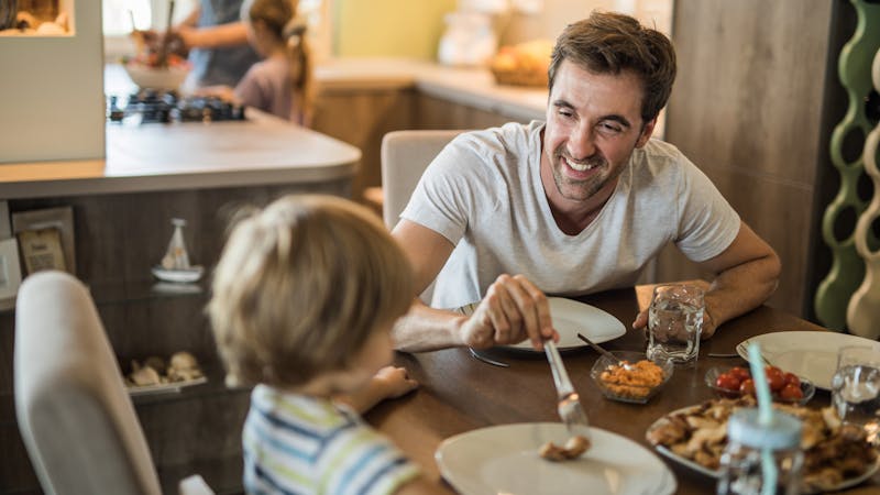 Happy father enjoying with his son at dining table.
