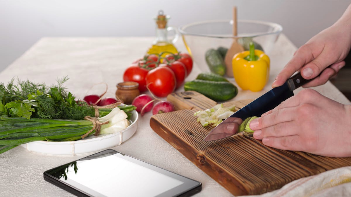 young man prepares healthy vegetable salad. Cook’s hands close-up, healthy eating