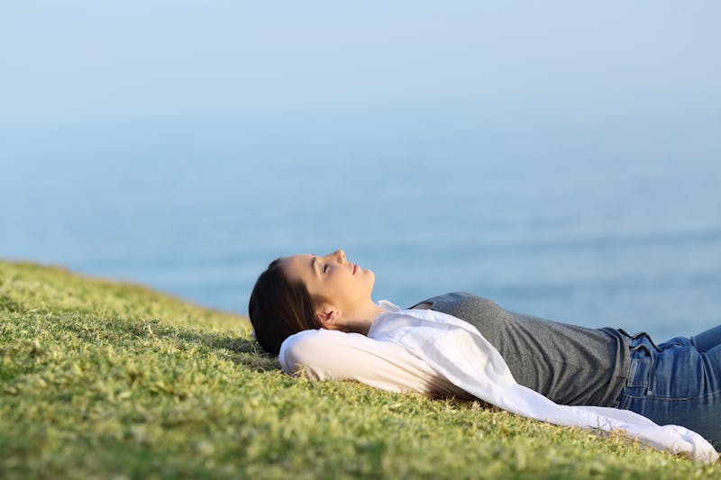 Relaxed woman resting on the grass in the coast