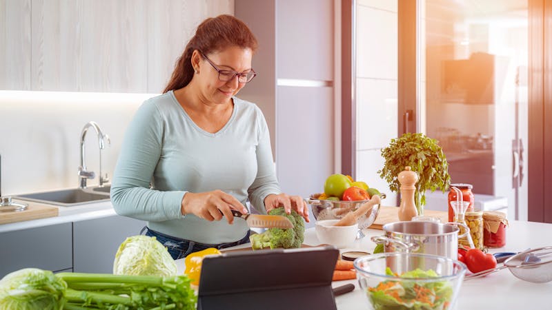 Happy woman cooking healthy vegan food