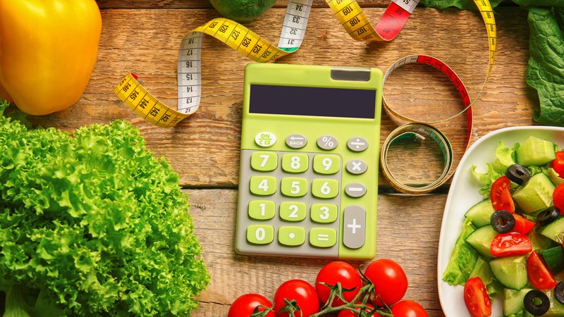 Calculator, measuring tape and set of healthy food on wooden table