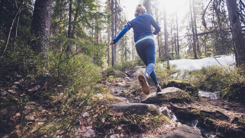 Woman trail runner running in forest.